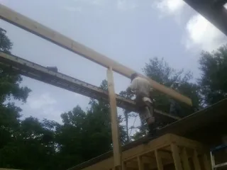 Carpenter setting a ridge beam over a new addition frame — Ice Dam Removal by Roofing Brothers in Eastpointe