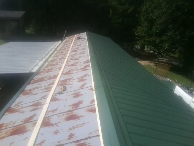 Old rusted panels beside newly installed green metal roofing — Wind Damage Roof Repair by Roofing Brothers in Eastpointe