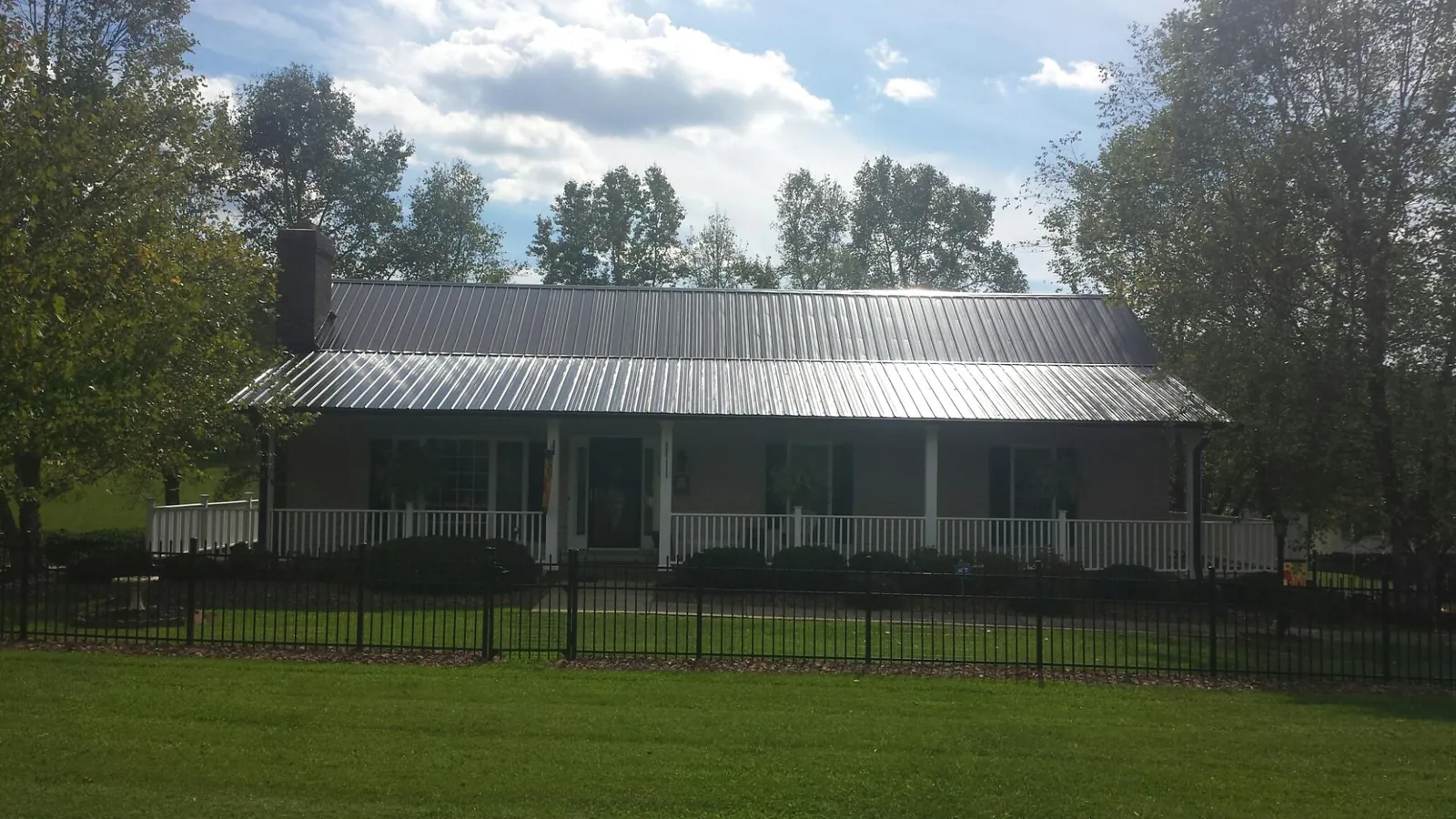 Gray metal roof on a brick ranch with a full width front porch — Gutter Guard Installation work by our crew in Eastpointe