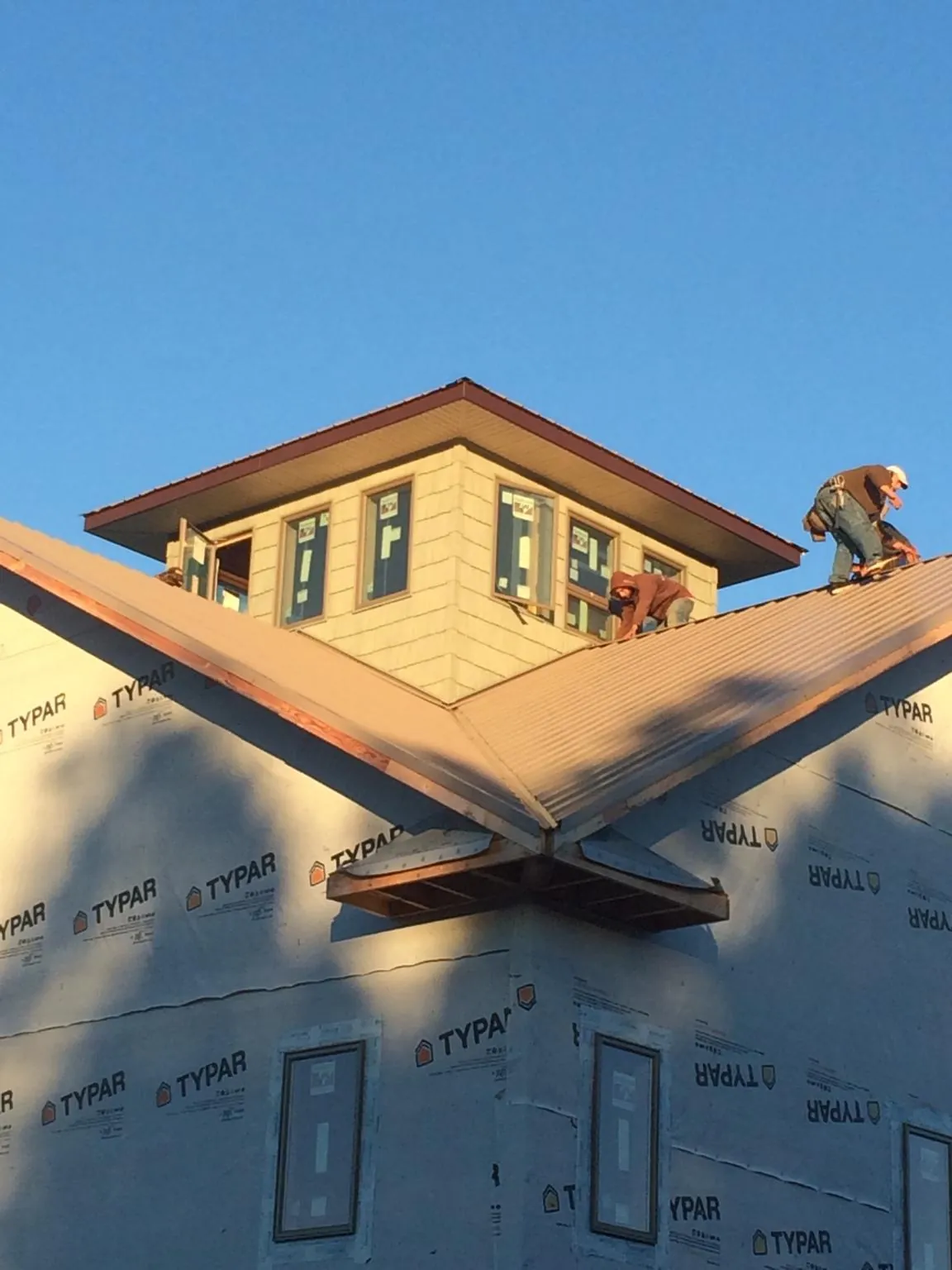 Roofers working around a rooftop cupola on a new metal roof at sunset — Roof Waterproofing in Eastpointe by Roofing Brothers